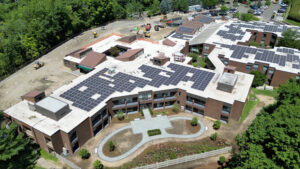 Screenshot - Waveny Aerial view of a multi-building campus with extensive rooftop solar panels and a construction site at the edge.
