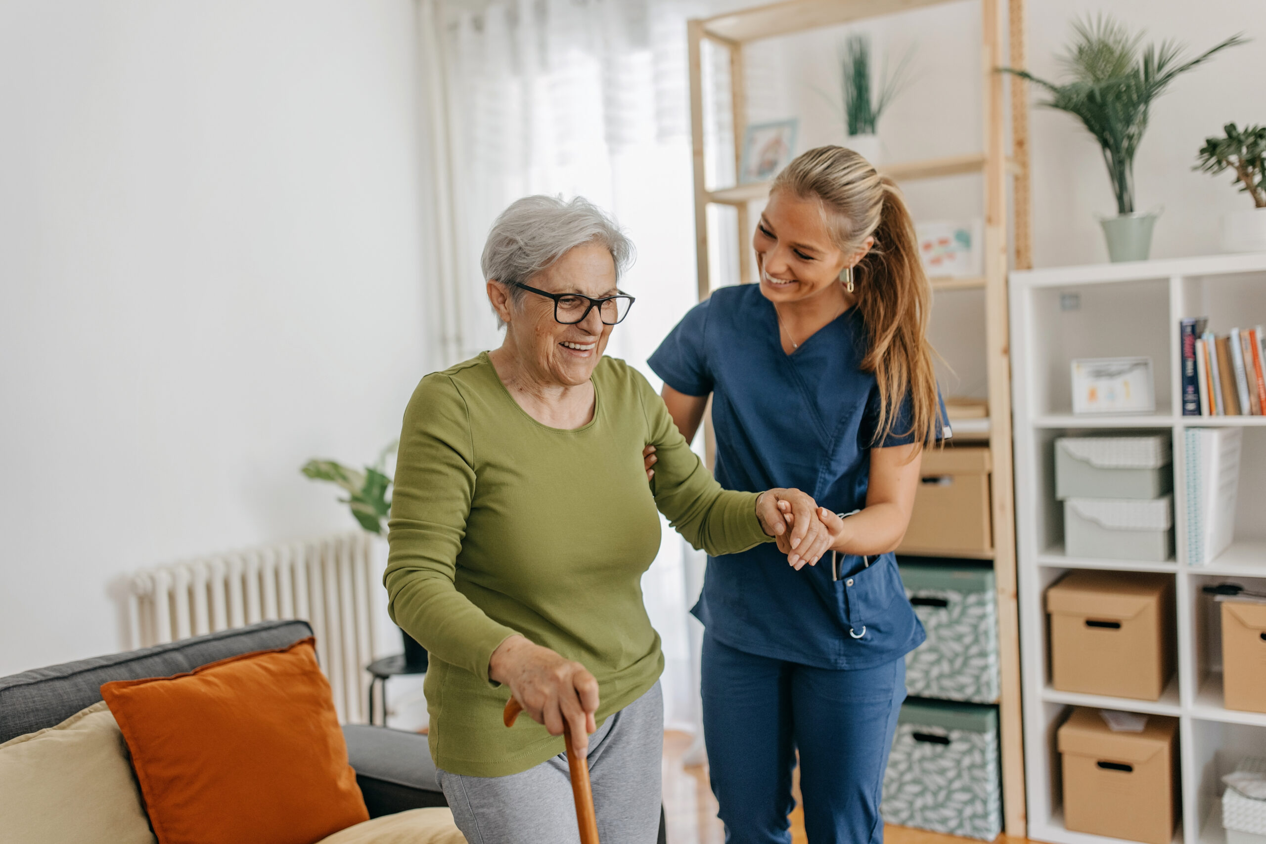 Home health nurse assisting a patient walking at home
